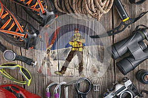 Top view of rock climbing equipment on wooden background. Chalk bag, rope, climbing shoes, belay/rappel device, carabiner and asce