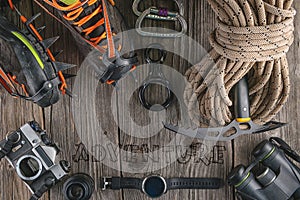 Top view of rock climbing equipment on wooden background. Chalk bag, rope, climbing shoes, belay/rappel device, carabiner and asce