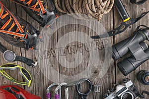 Top view of rock climbing equipment on wooden background. Chalk bag, rope, climbing shoes, belay/rappel device, carabiner and asce