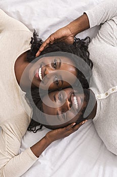 Top view of romantic afro couple lying in bed together