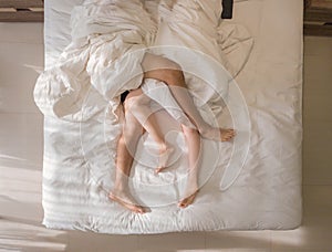 Top view of romantic couple sleeping. bare feet of their legs lying in a bed with white blanket in love and sex concept in modern