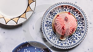 Top view of Rose and Lychee Mousses Cake decorated with rose petals in blue and white porcelain plate on marble background