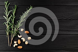 Top view of rosmarin leafs and nuts on black wooden background. photo