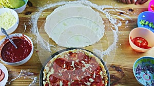 Top view at round dough with oil drops served next to ready baked pizza on table