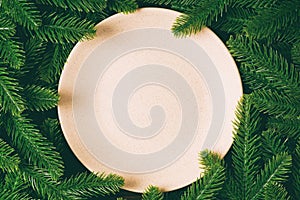 Top view of round festive plate on fir tree background. Christmas dish concept with empty space for your design