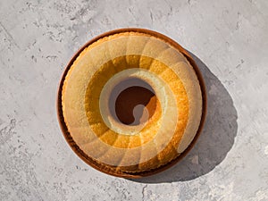 Top view of a round manna pie in a clay brown plate on a gray neutral background.