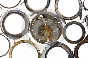 Top view of round silver cases from wristwatches and clockwork with gears. Empty metal dials from old wristwatches on