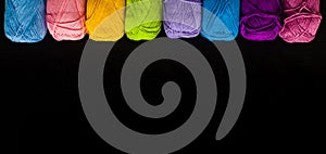 Top view row of rainbow yarn balls on the black