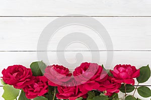 Top view of row of red roses on white wooden background, photo