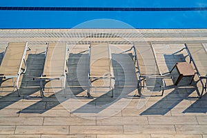Top view row of sunlounger chairs near a outdoor swimming pool with blue water