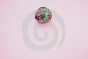 Top view of a rubber ball made out of rubber bands isolated on a pink background