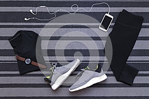 Top view of running shoes, womens clothes, pants tights, smartphone run application isolated on grey carpet