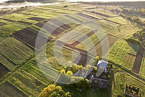 Top view of rural landscape on sunny spring day. Farm cottage, houses and barns on green and black fields. Drone photography