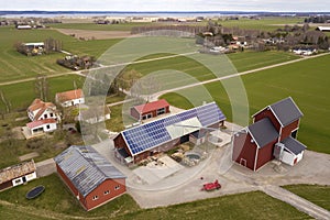 Top view of rural landscape on sunny spring day. Farm with solar photo voltaic panels system on wooden building, barn or house