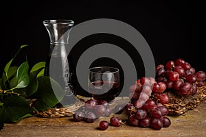 Top view of rustic bottle, glass with red wine and grapes on wooden table