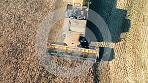 Top view of a rye field getting reaped by an agricultural vehicle