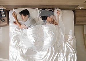 Top view of sad Asian couple sleeping together, thinking about relationship problems, and suffering from depression on bed with