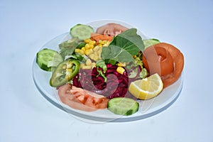 Top view of salad with pepper, tomato, cucumber, carrot, red cabbage and arugula, lemon, onion