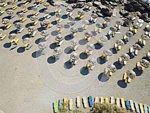 Top view on sandy beach with blue and yellow sunbeds and parasols
