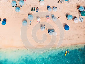 Top view of sandy beach with turquoise sea water and colorful blue umbrellas, aerial drone shot