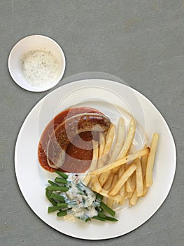 Top view Sausage and boiled Vegetable with Cream Sauce and French fries on a white ceramic plate,grey floor background