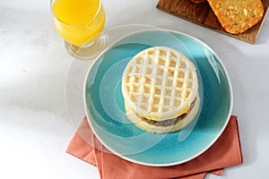 Top view of sausage egg cheese waffles sandwich with hash browns