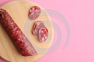 Top view of sausage on a wooden chopping board isolated on a pink background