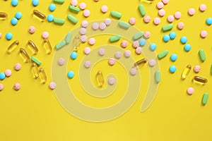 Top view of scattered bright pills on a yellow background
