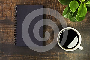 Top view of School notebook with Plant and Coffee cup on wooden table background. Business, office or education concept