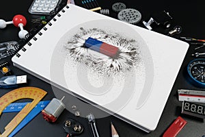 Top view of science school accessories desk with science laboratory, blank paper and bar magnet magnetic field on black background