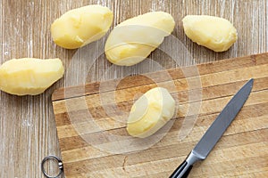 Top view of scrubbed boiled potatoes in jackets on the wooden background
