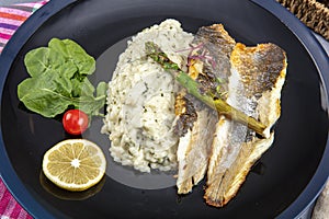 Top view of Sea bass fillet steak with vegetable in black round plate