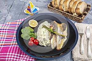 Top view of Sea bass fillet steak with vegetable in black round plate