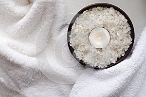 Top view of sea salt, candle, white towels.Concept of spa treatments