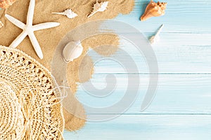 Top view of sea straw hat and sea shells on the sea sand on a blue wooden background, Summer concept on empty blue wood floor and