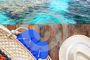 Top view of sea and wooden deck with beach accessories