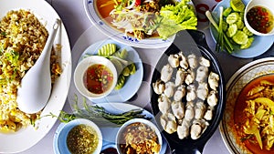 Top view of seafood meal with fresh oyster, stir fried crab with curry, fried rice, Thai spicy horseshoe crab egg Salad