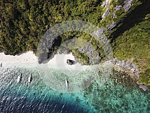 Top view of a secluded beach and three boats in Entalula Beach, El Nido, Palawan. Forest, beach and reef dropoff photo