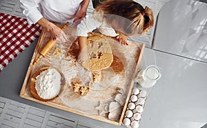 Top view of senior grandmother that with her little granddaughter cooks sweets for Christmas on the kitchen