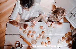 A top view of senior grandmother with small toddler boy making cakes at home.