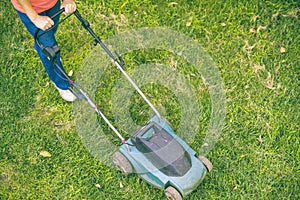 Top view of senior man using lawn mower on grass field