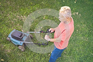Top view of senior man using lawn mower on grass field