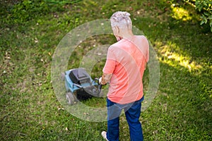 Top view of senior man using lawn mower on grass field