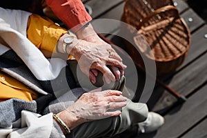 Top view of seniors holding hands, having romantic moment during autumn picninc near lake.