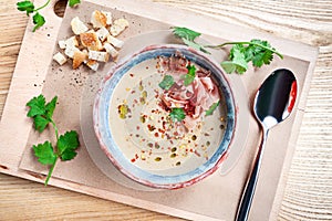 Top view on served cream soup with jamon, parsley and bread on wooen background. Flat lay food for lunch. Copy space for design.