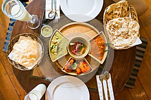 Top view of served Indian cuisine dishes in bowls and white plates