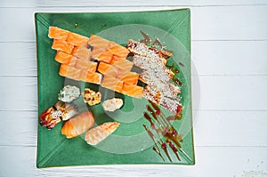 Top view on set of assorted roll and sushi on green plate isolated on white wooden background. Sushi with salmon, eel. japanese