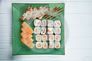 Top view on set of assorted roll and sushi on green plate isolated on white wooden background. Sushi with salmon, eel. japanese