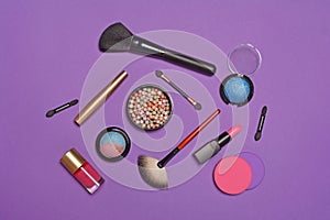 Top view on set of beauty products as decorative cosmetics and makeup brushes on purple background