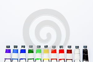 Top view set of colored tubes on white drawing pad background, copy space